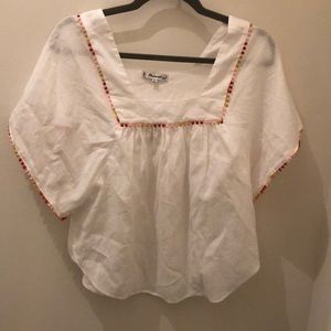 A white shirt with detailed Pom poms